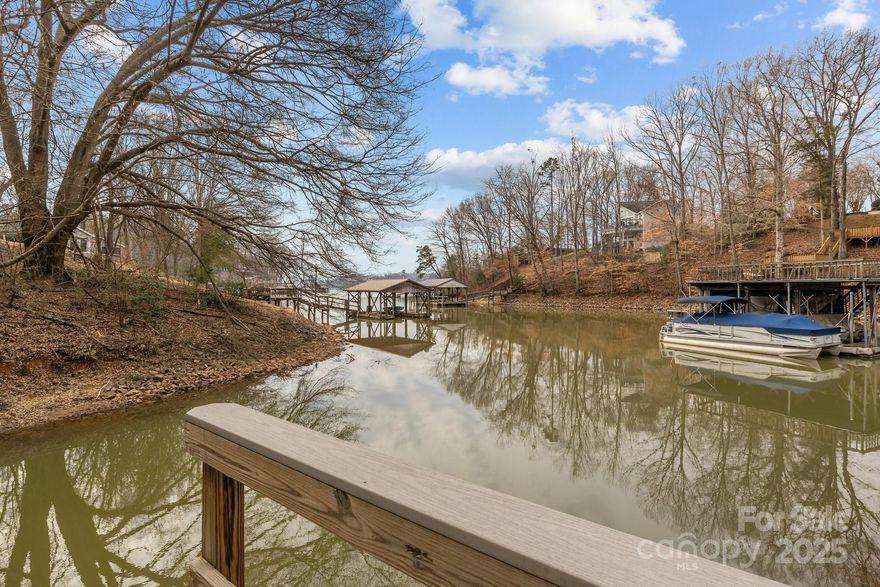 This charming lake house offers the perfect getaway with stunning water views and a relaxing atmosphere. Nestled on the water, the home features a covered, wrap around porch, a patio off of the walk out basement, an outdoor shower, & a covered boat dock with a 6000 lb lift. Inside, you'll find a spacious open floorplan with a light-filled great room, thanks to a wall of windows providing a stunning view of the lake, making it the perfect indoor/outdoor entertaining area. The home includes three cozy bedrooms and three bathrooms, a loft, an additional room upstairs currently being used as a 4th bedroom, a large kitchen island,  making it an excellent choice for families. The unfinished basement provides endless possibilities for storage and customization with a bathroom already roughed in. Whether you're looking for a peaceful retreat or an adventure, this lake house is the ideal vacation spot for you or a short term rental. 2008 Stingray boat conveys.