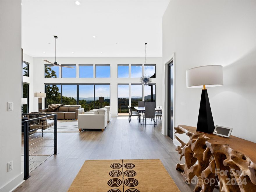 This beautifully crafted residence is a modern work of art designed to blend with nature’s beauty. The open layout offers a seamless flow with 14-foot ceilings in the living room and 10-foot ceilings throughout. The meticulous attention to detail is evident, with expansive windows framing the breathtaking southern mountain exposure. The sleek great room boasts a striking fireplace and opens to a chef's kitchen with custom cabinetry, Cambria countertops and waterfall island, and a butler's pantry/laundry room. A home office provides a private workspace. The main level primary suite is a serene retreat featuring dual bathrooms and walk-in closets. Two levels of decks enhance outdoor living, complete with a Hot Springs hot tub on the lower level. The lower level includes a well-appointed home gym, two additional guest rooms, and a shared bath. Outside, curated native plants, beautiful stonework and custom house marker featuring timed lighting elevate the tranquil mountain setting.