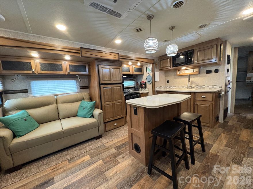 Resort living made easy—just bring your suitcase and start relaxing! 
This stylish 2017 travel trailer offers the perfect blend of comfort, convenience, and modern updates, creating a true “home-away-from-home” experience inside highly desirable Badin Shores Resort. Step onto the covered porch (roof added in 2021), fully set up for outdoor living with comfortable seating and ambient outdoor lighting— perfect for entertaining or unwinding after a day on the lake. Inside, the spacious living area is both inviting & functional, featuring a cozy fireplace beneath a wall-mounted TV.  The layout also includes a center island kitchen equipped w/ a propane gas range, microwave, refrigerator/freezer, pendant lighting & double sink. Two comfortable seating options; reclining loveseat added in 2024 and a pull-out sleeper added in 2022.  A pub style bar table with stools offers added dining space while opening up the floor space. The private bedroom offers ideal storage and a Queen size bed (the space can hold a king mattress). The bathroom has direct access from both the bedroom and the hall for added privacy & convenience.  The backyard provides a shaded retreat ideal for gathering around a wood burning fire pit that sits on a terraced pebbled stone patio area, along with a 10x12 storage building for all your lake toys and outdoor gear w/ much added convenience inside. Refrigerator in Shed conveys. Whether you’re searching for a weekend escape or a seasonal retreat, this property delivers comfort, style, and functionality. Additional recent updates include: refurbished deck with new handrails (2017), deck painted (2020), solar path lighting, metal roof on storage building (2023), fire pit and terraced yard improvements (2019 & 2021).  
BSR owners enjoy an abundance of amenities including a waterfront beach and w/ swimming area, outdoor pool, putt-putt, disc golf, sports courts, horseshoes, covered pavilions, picnic and grill areas, bath houses, fitness center, laundromat, Chapel, Restaurant and more. Conveniently located approximately one hour from Charlotte and Greensboro, with easy access to Asheboro, Albemarle, Salisbury, and surrounding areas. Don’t miss this opportunity to own your own lake getaway at Badin Lake. Cash Only Sale. Deeded lot with title to camper to be transferred at time of closing.