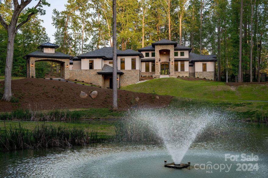 Discover unparalleled luxury in this brand-new masterpiece! Nestled on a large estate, this residence offers breathtaking views of a spring-fed, private pond. Immerse yourself in opulence from high-end finishes to an extraordinary lighting collection. Single-level living with soaring ceilings throughout. Open plan in the main living spaces & private bedroom suites. The primary suite is a sanctuary with a sitting area, morning room, dual walk-in closets & spa-like bath. Panoramic multi-glide doors seamlessly connect indoor & outdoor living, leading to several lanai areas & a charming interior courtyard. With a 4-car garage & porte cochere, this home exudes grandeur. 3771 sq ft basement, pre-plumbed for additional amenities, awaits your vision for expansion. Looking in Davidson, NC? This amazing opportunity for new construction is located in a gated community just 5 minutes from Davidson & near Cannon School, yet has much lower Cabarrus County taxes! The epitome of sophisticated living.