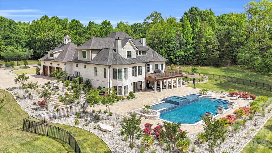 A truly rare offering just minutes from Charlotte, this extraordinary 20-acre luxury estate is a private sanctuary designed for refined living and unforgettable entertaining. Zoned for up to 3 horses with the option to add a barn or small barndominium, check CCR, the property features approximately 18 acres of scenic riding and exploring trails woven through serene natural surroundings. The residence is masterfully constructed with a reinforced poured-concrete foundation and engineered framing, wrapped in full masonry with striking oozing mortar joints. Architectural Glenwood shingles, solid cedar garage doors, iron entry door, and cedar exterior trim set a tone of timeless craftsmanship. Inside, solid oak flooring rests on a double-layer, moisture-resistant subfloor, complemented by solid wood Cutter doors with Emtek hardware throughout. The thoughtfully designed main level offers a luxurious primary suite and an exceptional private guest suite. At the heart of the home, the chef’s kitchen showcases custom cabinetry and premium finishes, seamlessly flowing into elegant gathering spaces. A mahogany wine cellar, Lutron lighting, and integrated Sonos system elevate everyday living. Infrastructure is equally impressive with three tankless water heaters, four furnaces, 600-amp electrical service, and four whole-house generators, along with a comprehensive security system featuring central monitoring and surveillance. Step outside to a covered Brazilian Ipe deck overlooking breathtaking grounds highlighted by extensive landscaping, full exterior lighting, and Hunter irrigation. The spectacular lower level is an entertainer’s dream, while the resort-style heated and cooled pool creates a year-round oasis. With remarkably low road maintenance costs and a setting that blends seclusion, luxury, and convenience, this one-of-a-kind estate offers an unparalleled lifestyle—where privacy, craftsmanship, and elegance meet.