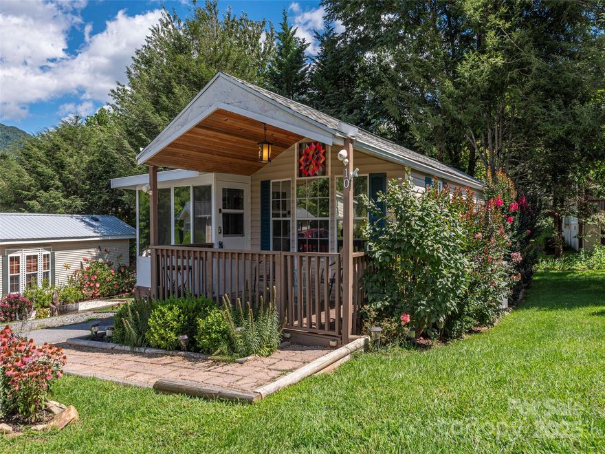 If you are looking for low maintenance and efficient living in the middle of the Appalachian Mountains, this immaculate park model home is just for you! It has the benefit of a two bedroom cozy home with lots of additional storage, a neat little shed and outside entertaining space. A well thought out layout includes two bedrooms and a sunroom, screened in porch and a deck by a small stream overlooking green space. This peaceful retreat comes fully furnished. New fan. New flooring. Updated faucet. Reconditioned deck with pet ramp. Upgraded landscaping and year round mountain views. Elk often graze in the pasture beyond. 50+ Community. No Short Term Rentals Allowed. Close to all of Maggie Valley's amenities, 15 minutes to Waynesville, 35 minutes to Asheville and just over the mountain from Cherokee.