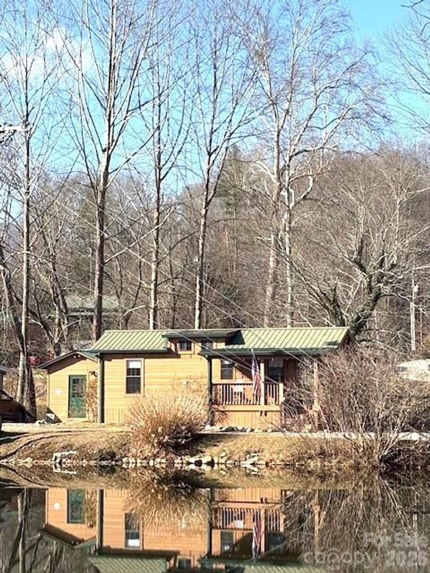 A REMARKABLE & PICTURESQUE SETTING... the front of this home overlooks a large lake and distant mountain views; the back of this home overlooks a rushing mountain creek. Located in the Jonathan Valley area. This "cabin-style" park model home has cathedral-style tongue and groove wood ceilings with wood beams, tongue and groove wood walls, and wood floors throughout. Two bedrooms with split design, two full bathrooms, living room, modest but fully functional kitchen, and a dining area. The upper loft area provides additional sleeping space for the little ones; they'll love the climb up the ladder (this area not counted in square footage). Ceiling fans with light fixtures throughout. Central heat and air. Public water and sewer. The exterior siding is wood; log-style. Metal roof. The front porch is covered; to enjoy the views, rain or shine. The side deck is open, of good size, and a great spot to barbeque; there are stairs that lead down to the creek. The 10' x 10' out-building on the side has electrical outlets and overhead lighting. This home is nestled within Dogwood Lakes; a close-knit community that is suitable for year-round or seasonal use. Valley-floor setting with level year-round access. Close to Maggie Valley, Waynesville, Cataloochee Valley in the Great Smoky Mtns National Park. 30-40 minutes to Asheville. Nearby restaurants, shops, entertainment, outdoor activities, & major roadways.