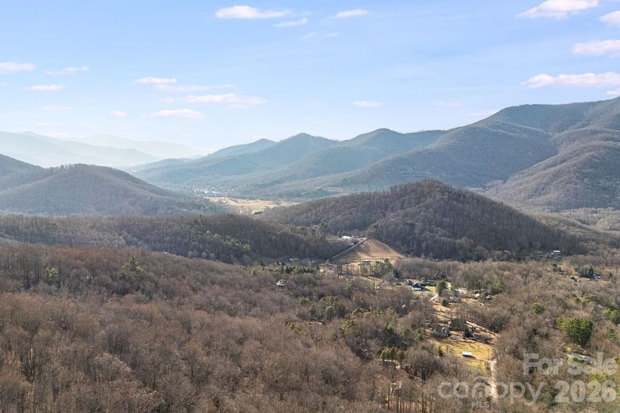 Ranging from approximately 3,150’ to 3,850’ in elevation, this ±9.77-acre gated mountain sanctuary is a true paradise in the coveted North Fork Valley/Asheville Watershed. Exceptionally private yet remarkably convenient, the property lies just minutes from downtown Black Mountain—named “America’s Prettiest Small Town”—and a short drive to Asheville and the Asheville Regional Airport. 
This exceptional property provides stunning sunsets and sweeping west-facing views toward the Asheville Watershed, Blue Ridge Parkway, Craggy Gardens, and the surrounding mountain ranges. As you rise in elevation, the scenery becomes increasingly dramatic, with year-round vistas possible through selective clearing. Pristine, mature forest and lush rhododendron ensure enduring privacy and serenity, creating a tranquil, cool-elevation retreat that feels worlds away.
The land adjoins conservation acreage on two sides, including a 123-acre tract protected by the Southern Appalachian Highlands Conservancy. This unique setting enhances seclusion and offers access to rich biodiversity and old-growth woodland—an ideal environment for hiking, exploring, and experiencing the region’s natural abundance. Multiple potential building sites exist across the sloping-to-steep terrain, with some portions of the tract subject to Steep Slope Ordinance and Protected Ridge Overlay requirements. Walker Mountain Lane, a well-maintained gravel roadway, provides smooth, reliable access to this mountain sanctuary, with no need for four-wheel drive—ensuring seclusion without sacrificing ease of reach. The seller is subdividing the full ±18.27-acre property and offering this ±9.77-acre tract separately, which will include a 20ft wide right-of-way to provide access to this portion of the parcel.
Just 10 minutes away, Black Mountain offers a vibrant complement to the property’s pristine solitude. This artistic enclave—once home to the iconic Black Mountain College—buzzes with creative energy. Its walkable downtown is lined with galleries filled with local craftsmanship, cozy bistros serving mountain-inspired cuisine, and a deep sense of history and culture woven into every storefront.
Whether envisioned as a private estate, second home, family compound, or vacation retreat, this cool-elevation oasis has it all. With unmatched privacy, dramatic mountain scenery, and easy access to one of the region’s most inspiring small towns, this is truly a rare and unique find in Western North Carolina. No drive-bys due to gate.