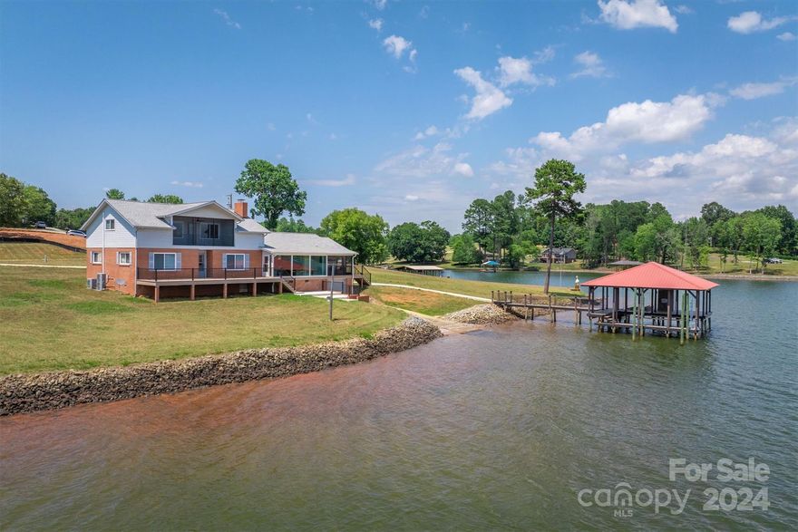 RARE OPPORTUNITY to own a main channel water front home without HOA/CCRS/city taxes! This home can also pay for itself if utilized as a short term rental sleeping up to 14 w/ similar rentals making 80-100K per year. Home received a permitted/ professional remodel & comes 100% furnished! Amazing open water views from floor to ceiling commercial windows on main floor. Even more rare is the over acre flat lot w/ 300ft of water front & boat garage w/ launch. Upgraded...floors, all baths, cabinets, windows, quartz counters, doors, plumbing, electrical, almost everything! HUGE open living, kitchen, dining area w/ enough room for pool table. Luxury kitchen w/ walk-in pantry & coffee/ beverage station. 3 bedrooms on main...primary has a stylish private bath. Upstairs is the open concept bonus room w/ 3 built in queen beds, 2 walk-ins & screened in upper porch! NEW stationary dock featuring a boat slip, space for 2nd boat slip w/ poles, 2 jetski slips, platform area all covered w/ remote lifts!