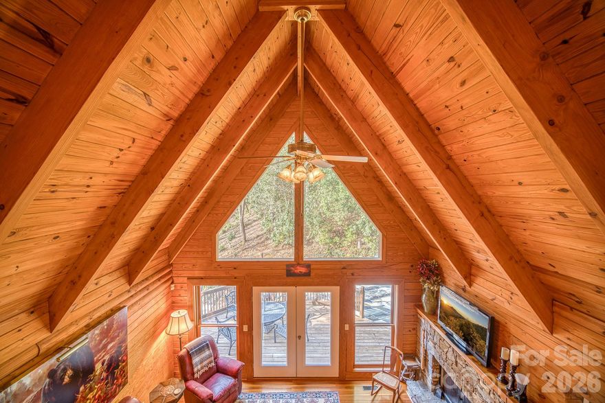 Tucked into a peaceful wooded setting in Lake Toxaway Estates, this charming mountain cabin offers the perfect blend of rustic character and comfortable living. The dramatic great room features soaring vaulted wood ceilings, exposed beams, a stunning wall of windows, and a stone fireplace that anchors the open living space.

The kitchen is designed for easy entertaining with granite countertops, warm wood cabinetry, and a center island overlooking the dining and living areas. Multiple bedrooms provide comfortable accommodations for family and guests, while the finished lower level offers a spacious recreation area ideal for games, media, or additional gathering space. Ideal as a private mountain getaway or potential vacation rental investment.

Enjoy outdoor living on the covered front porch, screened porch, or private stone patio, complete with a built-in grilling area—perfect for relaxing or entertaining in the mountain air. Set on a beautifully wooded lot with a waterfall feature, this property offers privacy, natural beauty, and plenty of space both inside and out.

Whether you’re searching for a full-time residence, weekend retreat, or mountain getaway, this inviting cabin delivers the best of mountain living. Short-term rentals are allowed! Access to Lake Toxaway’s marina, pickleball, outdoor swimming pool, golf, and so much more is based on membership availability and application to the Lake Toxaway Country Club.