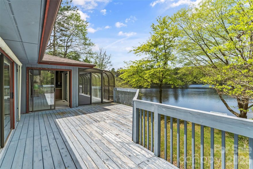 Lakefront living in a peaceful natural setting! This beautiful home features lake views and an open floor plan designed for comfortable living. The living room showcases a stone wood-burning fireplace that adds warmth and character, while the sunroom offers stunning water views—perfect for relaxing or entertaining. The kitchen includes stainless steel appliances, ample cabinetry, and views of the lake. The primary suite features a private bath and a porch overlooking the water. A spacious recreation room with a brick wood-burning fireplace and woodstove insert, full bath, and walk-out access provides flexible space for a home office, studio, or guest area. Enjoy a level yard with a stationary dock, ideal for lakeside gatherings. Additional features include a 2-car garage, carport, and generous driveway parking. Located in the gated Connestee Falls community with access to golf, clubhouse dining, tennis, pool, hiking trails, fitness center, and more, with convenient access to nearby shopping and amenities. A wonderful opportunity to enjoy lakefront living.