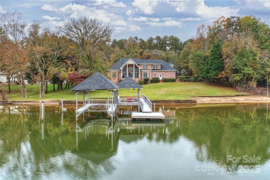 RARE FIND - like NEW lake home! Custom built, full brick w/breathtaking views of Lake Wylie, situated on a spacious hard to find flat lot in desirable Fort Mill. Meticulously renovated from top to bottom, this beautiful home welcomes you w/a soaring 2-story foyer + curved staircase, formal dining, private office & 2-story great rm w/unmatched views, built ins & gas fireplace. Kitchen w/huge center island, new appliances, abundant cabinets & walk in pantry. Primary suite located on main w/2 walk-in closets & a stunning bath w/separate vanities, freestanding tub & oversized tile shower. 3 oversized BRs/2 bths up incl 1 BR w/en-suite, sitting area & walk-in cedar-lined closet. Lg bonus rm w/walk-in closet. Solid wood floors throughout, designer lighting & neutral paint. Newer roof & HVAC. Unwind on the covered rear porch overlooking the lake. 3-car garage + workshop offers space for projects & storage. Private dock w/covered boat lift + jet ski lift & jet ski launch + a sandy beach area!