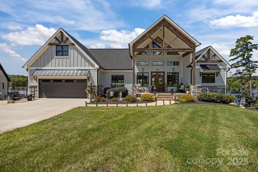 A stunning waterfront retreat! Enjoy deep water access to High Rock Lake with your own private dock & covered boat lift! This custom designed home features an open floor plan, soaring vaulted beamed ceiling, & floor to ceiling stone fireplace flows into the chefs kitchen with 8’ quartz countertop island. Main level includes 2 spacious bedrooms & 2 full bathrooms. A serene primary suite boasts an en-suite with heated tile flooring. Finished basement with kitchenette & walk-out French doors access, & 2 additional bedrooms & 2 full baths. A second-story carpeted bonus room offers flexible space. Unwind in the private sauna or enjoy the convenience of the elevator. Outdoor living shines with sunny deck & screened in porch with unobstructed view of the lake! Lower level hosts a covered patio with a separate stamped concrete fire pit area. A series of stone slab steps adorned with large stone retaining walls, meticulous landscaping throughout, & 3-car garage completes this incredible lake home.