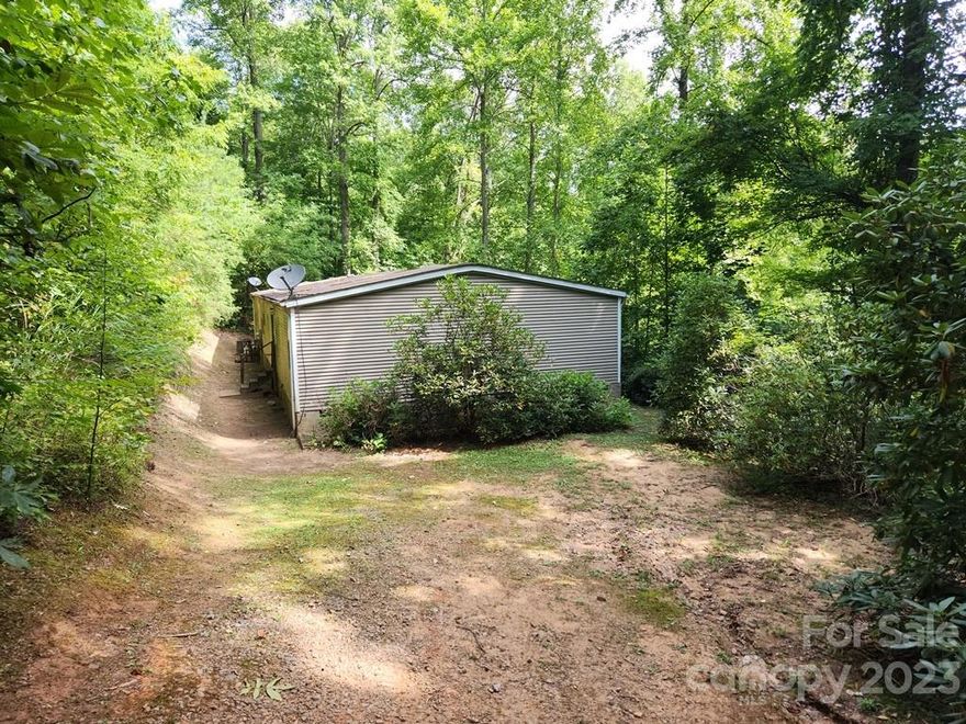 Manufactured home tucked away on 1 acre wooded lot. Approximately 15 minutes to I-40 and 20 minutes to downtown Asheville. Home features an open, split-bedroom layout that includes kitchen w/ island, dining room, living room, den and large primary bedroom suite w/ office. Awaiting new owners to renovate and make their own.