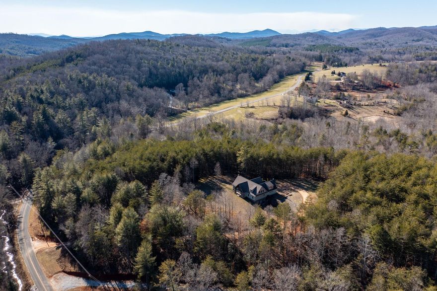 This gorgeous home sits on 10 acres in the Ellendale community of Alexander County!  The beamed, craftsman style exterior flows seamlessly with the rustic landscape known as Houck Mountain. Beautiful hardwood floors, vaulted ceilings and stone fireplace bring the outdoors inside.  Enjoy the early morning sunrise from your rocking chair front porch, and evening sunset bbqs on the large, covered back entertainment porch.  There is room for your hobbies, boat or extra cars in the large basement and additional detached workshop/garage.  The upstairs serves as a wonderful storage area, or refinish and enjoy extra living and entertainment space!
Stay extra toasty warm on those cold winter days with the supplemental heat woodstove in the basement!