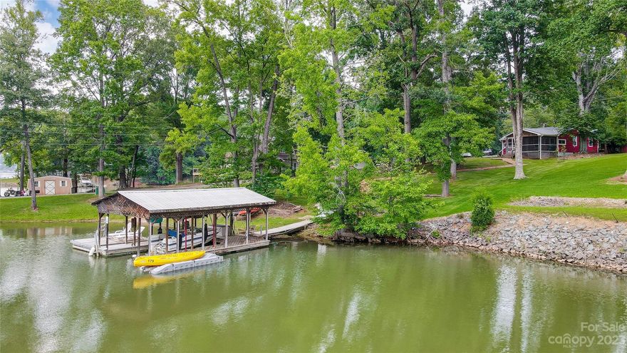 Designed to enjoy the outdoors, this classic waterfront cottage is on a gently sloping lot with mature trees, plenty of open lawn, beautiful natural shoreline, and offers a private boat ramp.  Nestled on a serene cove opening to the main channel, the best of both worlds. The Huge screened porch and covered dock are fantastic spots for outdoor entertaining or just to relax & take in the glorious views. Perfect for a weekend retreat or full-time living this waterfront gem is loaded with character and ready for you to put your personal stamp on it. Interior boasts one level living- kitchen opening to great room and dining area with plenty of windows to enjoy the lake views. Looking for peace, serenity & relaxation then this is the house for you!  Delivering that “away from it all” feeling yet only minutes to shopping, dining, 485, airport & Uptown Charlotte.