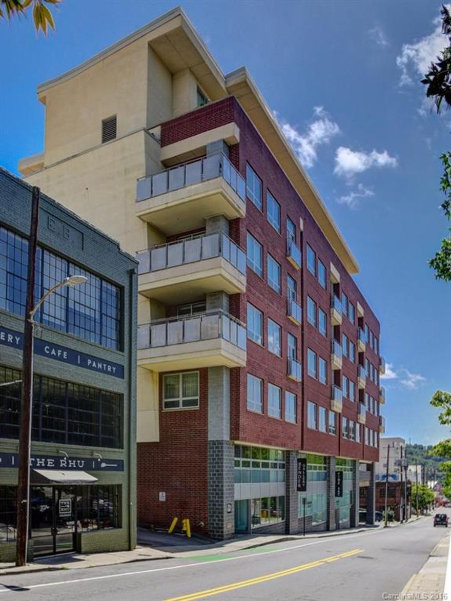 Upscale condo with a modern touch located in the center of downtown Asheville.  Walk to everything.  This spacious 1 bedroom condo has an open layout with 12ft ceilings, SS opening windows, exposed beams and metal duct work.  Fine finishes include stainless kitchen counter top, granite on bar top and bathroom, travertine tile in Jacuzzi tub/shower, and solid birch doors.  Office space with built-in desk and shelves off bedroom.  Great views from rooftop terrace. Secure parking in building.