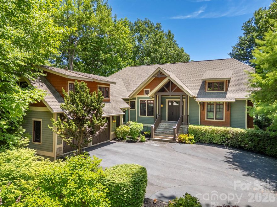 Perched above Tom Fazio’s signature 13th hole, 161 Chattooga Run captures the essence of mountain golf course living within Champion Hills, Hendersonville’s premier golf community. Thoughtfully crafted by respected builder Mike McDermott and later enhanced by renowned builder Paul Taylor, this home blends timeless craftsmanship with inviting spaces designed for gathering, relaxation, and enjoying the beauty of Western North Carolina.
From the moment you arrive, the setting feels special. Tucked into a private homesite with stair-step views overlooking holes #13 and portions of #12, the property offers a rare sense of seclusion with no neighboring homes in sight. Lush landscaping, layered outdoor living areas, and the peaceful sound of water create a true mountain retreat atmosphere.

At the heart of the home, the great room opens effortlessly onto the rear patio where summer dinner parties, evening cocktails, and quiet mornings become part of everyday life. A double-sided fireplace adds warmth and ambiance both indoors and out, while the adjacent side deck overlooks one of the property’s most captivating features—a stunning approximately 37-foot waterfall designed and maintained by Water Dance, featuring 12 individual cascades that blend naturally into the landscape.

The kitchen and dining spaces are warm, functional, and rich with custom details, including thoughtfully designed built-ins and elegant pullout serving boards that add charm and practicality. Just beyond, the temperature-controlled sunroom an addition completed in 2016 provides the perfect setting for morning coffee, reading, birdwatching, or catching up with friends while surrounded by natural light and tranquil views.
The 2016 addition by Paul Taylor also transformed the detached garage into an attached garage through an enclosed breezeway and created a spacious suite above the garage complete with a full bath, closet, and storage. Whether used as a guest suite, office, media room, or private retreat, the flexibility enhances the home’s livability.

Designed for entertaining and relaxed mountain living, the lower level offers inviting spaces for game nights, wine tastings, and gatherings around the custom wine cellar with its beautifully arched handcrafted door. Guest suites, walkout access to the outdoors, and a golf cart garage complete this exceptional mountain retreat.

With 3–4 bedrooms depending on lifestyle needs, exceptional privacy, curated outdoor living, and direct connection to Champion Hills’ celebrated golf course lifestyle, 161 Chattooga Run offers a rare opportunity to enjoy mountain living in comfort, elegance, and style just minutes from Hendersonville’s charming downtown, dining, shopping, hiking, and cultural attractions.