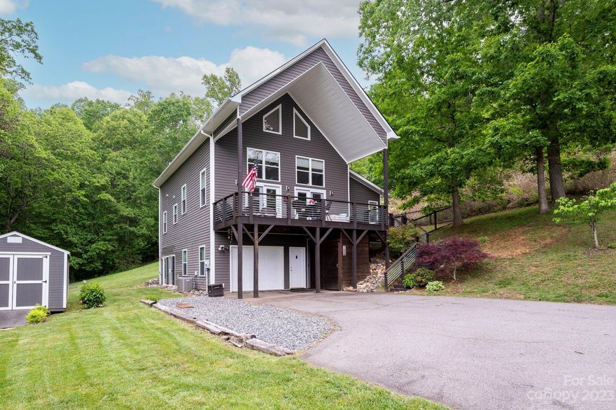 Peaceful and private, this low-maintenance, 1.5-story A-frame is the perfect contemporary mountain cottage, with fantastic views of the Blue Ridge from its fantastic covered front porch! Main living area features a wall of windows that floods the home with sunlight, plus a wood-burning stove for chilly evenings. The open-plan kitchen with stainless steel appliances is fit for a chef, and you're sure to enjoy the vaulted ceilings, luxury vinyl plank flooring, and more in the loft-style primary suite. There's also a finished lower level, perfect for a home gym, studio, office, or bonus room — and plenty of outdoor living in the fenced-in yard with storage shed, attached one-car garage, and flat, expansive driveway. Situated on a gorgeous and gentle 1.74 acres (two PINs: #9727452981 and #9727461015), only 5 miles from Mars Hill University, 20 minutes to Weaverville, and 30 minutes to vibrant downtown Asheville, this property would make an excellent primary residence or short-term rental!
