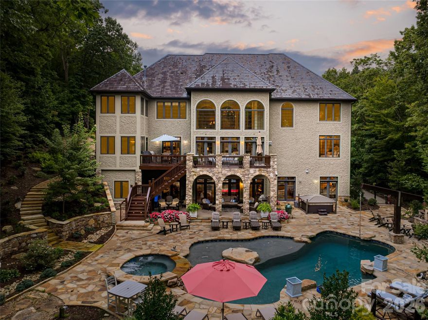 Behind the gates of prestigious Poplar Ridge, this refined residence is a statement of timeless grandeur and modern luxury. Exceptional craftsmanship is evident throughout, from soaring tray and coffered ceilings to arched doorways and rich Brazilian cherry floors. The open main-level design encourages effortless flow, centered around a gourmet kitchen with custom cabinetry, walk-in pantry and premium appliances. A sunlit breakfast nook and elegant formal dining room create inviting spaces for everyday living and special gatherings. Upstairs, the primary suite is a retreat, anchored by a fireplace and complemented by a spacious, spa-inspired bath designed for indulgence. Additional bedrooms and flexible living areas offer comfort and versatility for guests, work or recreation. Outdoors, the estate transforms into a private resort with a sparkling pool, expansive terraces, fire pit and hot tub, all surrounded by lush landscaping and mountain air. Within one of Asheville’s desirable gated communities, this Poplar Ridge home offers an elevated lifestyle defined by elegance, comfort and distinction.