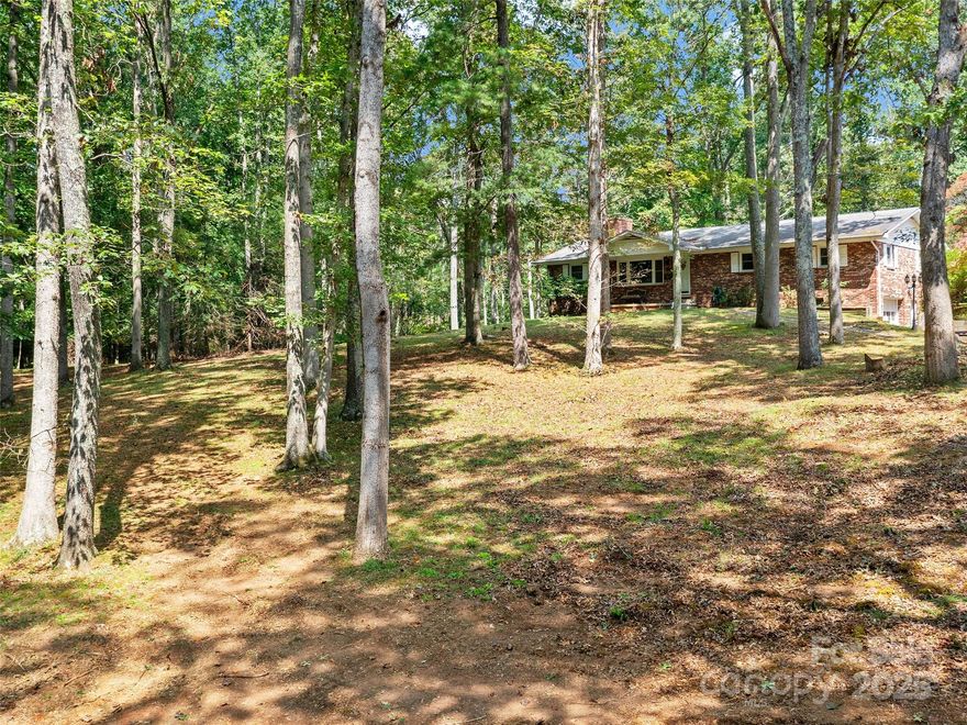 New Preliminary Soil Evaluation shows that the land could support 5 to 8 more septic systems/homes. First Time on the Market, this Family Retreat on over 10 acres (11.75 Deeded Acres) is in an Amazing Location! 15 minutes to Downtown Asheville but a world away. Multiple Building Sites on the Property, Open Use Zoning, Only County Taxes and Woodfin Water Available. The property is wooded, but trees could be cleared to create an incredible pasture for horses or Farming. This gently sloping property faces South West and the house is tucked up hill away from the road. This would make an Incredible Family Compound, Development, Farm or Much More.  Property can be developed because Woodfin Municipal Water is available for higher density. Buyer to Verify How Many Taps but the engineer said development is possible. The existing house has very good bones and plenty of space. A large one car garage on the main back of the house, another small garage in the basement, Hot Water Boiler Baseboard Furnace, Hardwood Floors under the carpet on the main level, an eat in kitchen, a primary bedroom with an attached bath! Open Use Zoning in the 28804 Zip Code!