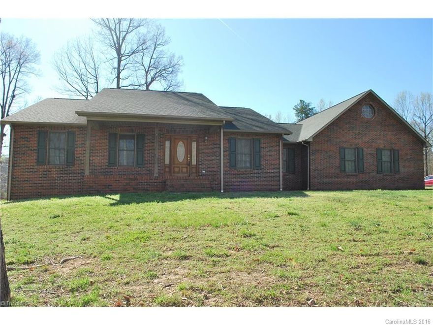 Brick ranch with large basement for expansion, plumbed for additional bath, large front and back covered porches.  Back overlooks watershed lake/spillway, hardwood and tile floors, custom built cabinets, rock fireplace, oversized garage, paved drive.