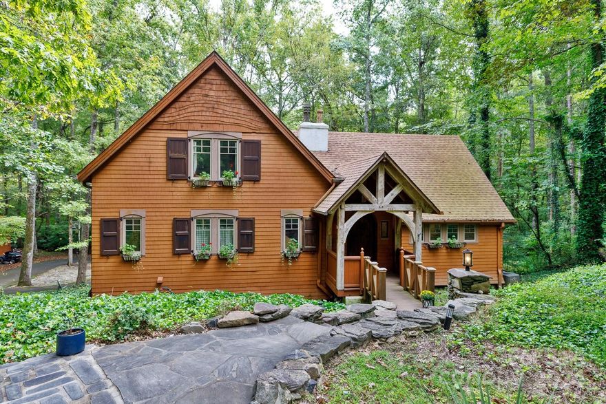Located in the serene Timbers subdivision and within the sought-after Clover Schools district, this unique European-inspired home sits on 3.162 private, wooded acres with a tranquil creek flowing towards the back of the property. The home exudes a cabin-like charm with vaulted ceilings, exposed timber beams, and rustic details throughout. The kitchen boasts a gas cooktop, wall oven, breakfast bar, and walk-in pantry, flowing into the open living and dining areas, highlighted by a cozy see-through fireplace. The primary suite features its own fireplace, a walk-in closet, dual sinks, a claw foot tub, and a separate tiled shower. Outdoors, enjoy the peaceful setting on the stone patio, complete with a whimsical stacked stone fireplace, perfect for relaxing by the woods and creek. A circular drive and large storage building add convenience to this one-of-a-kind home. Although the home has 4 bedrooms, the septic system is rated for 3.