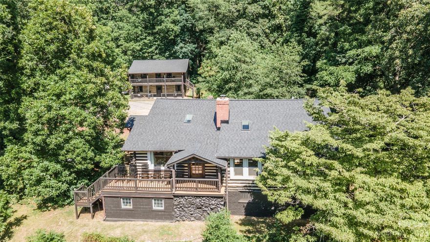 The charm of historic cabins combined with beautiful up-to-date design. Quiet, private setting but close to all Asheville has to offer. Nestled amidst the tranquility of historic log cabins, this property seamlessly blends classic charm with modern design. Just minutes (5.5 miles)  from the vibrant heart of Asheville, it offers a truly unique experience. The estate comprises two cozy log homes, housing three units that operate as successful short-term rentals (financials available upon request). Step inside to discover hardwood floors, naturally illuminated rooms adorned with skylights, inviting porches on every level, and Scandinavian warmth. The main lodge features a stunning two-sided stone fireplace, creating an ambiance of warmth and comfort. Additional information is available in the attached documents. New roof and HVA. Don't miss out on this extraordinary opportunity to own a piece of Asheville's real estate and tourism treasure.