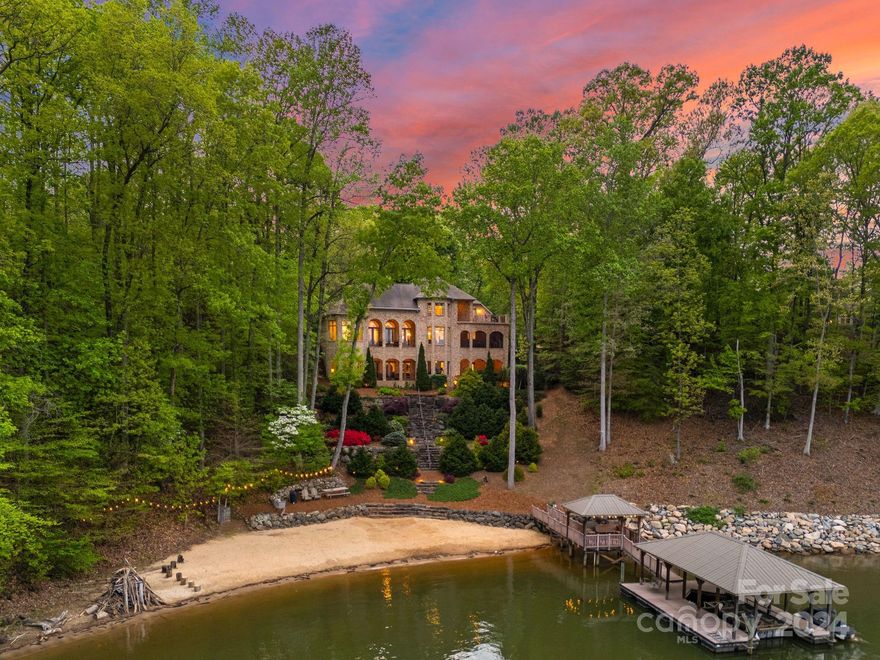 Serenity and luxury meet in this private waterfront oasis on the shores of Lake Norman. Embrace long range views, a beautiful natural sandy beach and private pier offering a picture perfect backdrop to elevate everyday living. Astoria, a private gated enclave of custom waterfront homes with 5 miles of walking trails and community garden. Take in the view as you enter this exquisite full brick and stone oasis. Well appointed kitchen overlooking the great room, steps away from the screened outdoor kitchen with dining area. Experience luxury in the main level owners suite with spa bath and veranda. Lake level offers lots of entertainment for everyone from movie room, billiards with fireplace, wine cellar, beautiful bar, fitness room and spa including a private guest suite. Boulders from the NC mountains lead you to your lake paradise. Prepare to be amazed!