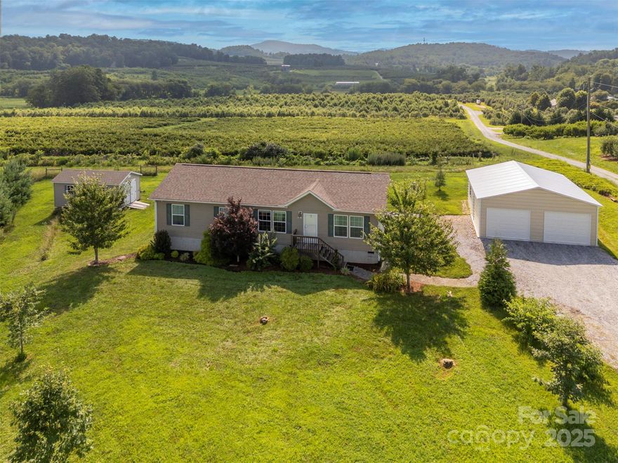 This beautifully maintained home features three bedrooms and two bathrooms, situated on almost an acre of mostly level land. This home features an open floor plan, creating a very spacious feel, complemented by drywall walls throughout. The primary bedroom is generously sized, and its en-suite bathroom includes a closet and vanity with double sinks. The kitchen offers ample storage and nice appliances, complete with a convenient breakfast bar. Enjoy peaceful moments or entertain guests on the back covered porch, which provides lovely mountain views—perfect for your morning coffee. This property also includes a 30x24 detached two-car garage, additional driveway parking, and a 12x20 shed with power in the backyard for excellent extra storage. Conveniently located, this home is just a short drive to downtown Hendersonville, as well as various shopping and dining options. I highly recommend scheduling a showing to experience this wonderful home in person.