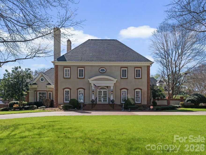 Timeless elegance with a modern-day twist defines this stately residence in the sought-after gated community of Seven Eagles. Situated on nearly an acre of private, gated grounds, this exceptional 6-bedroom, 7.5-bath estate welcomes you with a grand foyer with stunning marble flooring and a sweeping spiral staircase, flanked by a wood-paneled study with fireplace and a formal dining room, both showcasing beautiful trim work and craftsmanship rarely found in today’s new construction. The main level features a private guest suite with en-suite bath, as well as an expansive primary retreat with a dual-sided fireplace connecting the bedroom and spa-like bath, highlighted by dark green marble throughout and a sunken tub. A private staircase leads to an additional flex space ideal for a gym, office, or secluded lounge. The dramatic two-story living room is filled with natural light from wall-to-wall windows overlooking the backyard and seamlessly connects to the spacious kitchen, breakfast area, and inviting den with wet bar and fireplace—offering an open yet defined layout perfect for both entertaining and everyday living. Upstairs, you’ll find four additional bedrooms and a generous bonus room with wet bar, ideal for a secondary living or entertainment space. Outside is a one of a kind resort style oasis complete with a fountain, oversized pool, private whirlpool, separate pool bath and multiple gathering and lounging spaces.