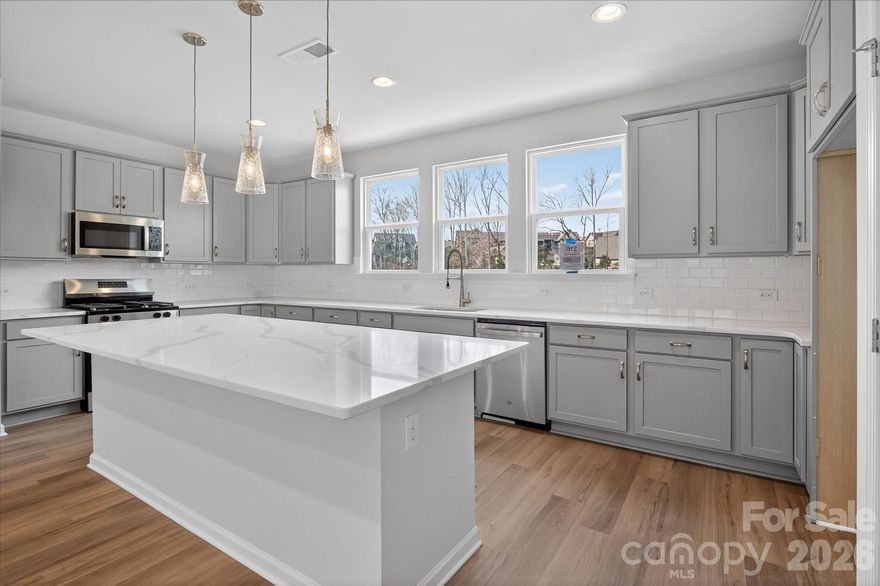 Enjoy the privacy of a first-floor guest suite and the convenience of a 2-car garage in this spacious 4-bedroom townhome. The main level features 9'ceilings, an open living area, and a private terrace, perfect for entertaining or relaxing outdoors. The kitchen boasts a large island with quartz countertops, tile backsplash, 42' cabinets, a double trash pull-out, and  stainless steel sink. It also includes a gas oven, range and dishwasher. Upstairs, the third floor includes a comfortable primary suite with a walk in closet and en suite bath with a tiled shower. Two additional bedrooms, another full bath, and a convenient laundry closet complete this level, offering plenty of space!