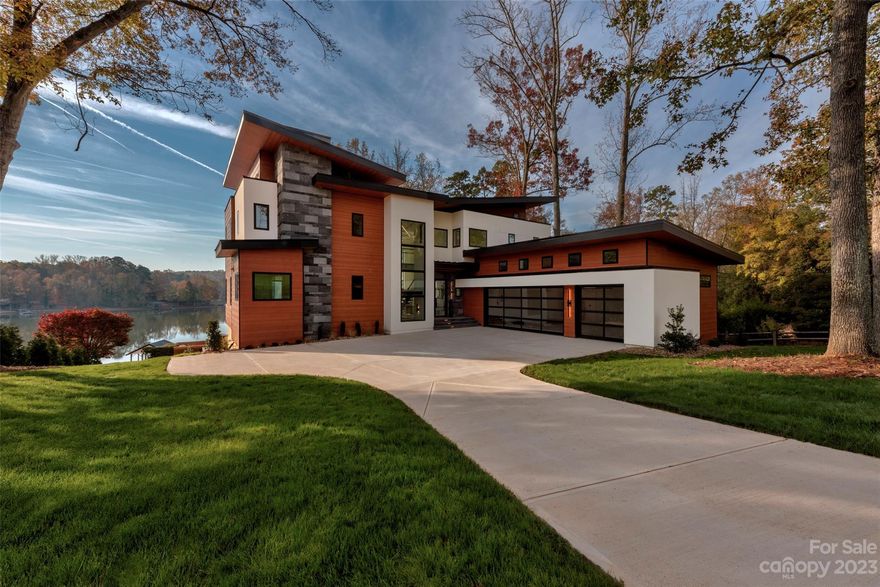 Experience luxury and privacy only 20 minutes from uptown Charlotte in this lakefront home brought to you by Artistic Contractors! Marvel at the sleek design, boasting smooth hard-coat stucco, Indonesian lava stone, and exotic South American cumaru wood. Step inside the 8ft glass door and see panoramic Lake Wylie views. The living room soars with 22ft ceilings and natural light flooding in. A stunning stone fireplace wall complements the steel accents. The primary suite offers private lake views and deck access. Indulge in the primary bath wet room with a  freestanding tub. The kitchen, fit for a chef, overlooks the lake and leads to a covered patio. A spacious basement below features a full bar and guest suite. Outside, the resort-style pool beckons, seamlessly integrated with the home. Enjoy the infinity edge, spa, and tanning ledge. An expansive pool deck invites entertaining. Outdoor amenities include a shower, built-in grill and dock with boat lift. Welcome to your lakeside home!