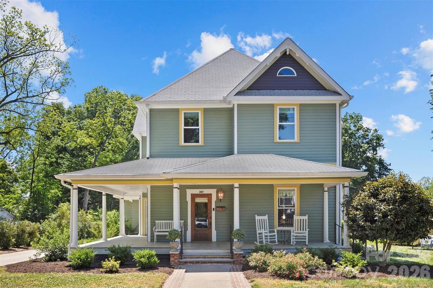 Step into a rare piece of Cherryville history at 207 W Academy Street—an early 20th-century home originally built in 1910, thoughtfully reimagined for today’s lifestyle while preserving its timeless character. Situated just moments from the charm of downtown, this residence reflects a period when craftsmanship, detail, and gracious living defined home design. Homes along Academy Street were known for their architectural presence and walkable proximity to the town center. This home showcases elements of the Victorian / Queen Anne Free Classic style, including its welcoming wraparound porch and classic proportions—beautifully restored and brought forward for modern living.
A standout feature of the renovation is the recreation of the upper level, thoughtfully added back to reflect the home’s original design—restoring both function and architectural integrity. Enter off the front wraparound porch through the original Solid, beveled glass front door where inside, historic charm meets elevated design with 10 foot ceilings throughout most of the home and original heart-of-pine and oak hardwood flooring. The front living area parlor welcomes you with an original fireplace surround adorned with mosaic tile surrounding the carved mantle, a true focal point and preserved piece of the home’s history. Just beyond, the dining room showcases a preserved tin coffered ceiling, offering a stunning nod to the craftsmanship of the era. An original beveled glass window centered on the west wall diffuses light in a cascade of rainbow prisms. The heart of the home is an enormous, fully modernized kitchen, beautifully designed with striking green cabinetry, upscale stainless appliances, Calcutta quartz counters, pot filler at the cooktop and ample space for gathering and entertaining around the large kitchen island. Adjacent, a vaulted-ceiling butler pantry and wet bar with Calcutta Maze quartz adds both character and functionality, while the adjacent main-level laundry room provides everyday convenience with quartz folding counter. The primary suite on the main level offers a private retreat, complete with a spa-inspired ensuite featuring vaulted ceilings, a large tiled walk-in shower, a soaking tub, and double shaver's height vanity topped with "leathered quartz"—perfectly blending comfort with luxurious features. The walk-in closet is built perfectly for anyone wanting stylish touches, custom designed. The separate water closet adds much privacy. 
Upstairs, you’ll find a thoughtfully designed second living area once a "sleeping porch"—ideal for relaxing or entertaining. This versatile space includes a built-in office nook tucked behind doors and an adjacent charming library area, creating flexibility for today’s lifestyle needs. Two additional bedrooms share a full bath with double vanity topped with quartz counters. One bedroom has a large window seat, full wall of built-in cabinets and storage. Set on a generous homesite, this property offers room to enjoy outdoor living while embracing the charm of a historic neighborhood.
The rear brick paver patio offers an additional outdoor living space, spanning an impressive 23 x 25 feet—perfect for entertaining and gathering. Every detail of this home reflects a careful balance—honoring its past while delivering the updates and layout of today’s buyer's desire. A place where history has been preserved, reimagined, and elevated into a truly modern charmer in the heart of Cherryville.