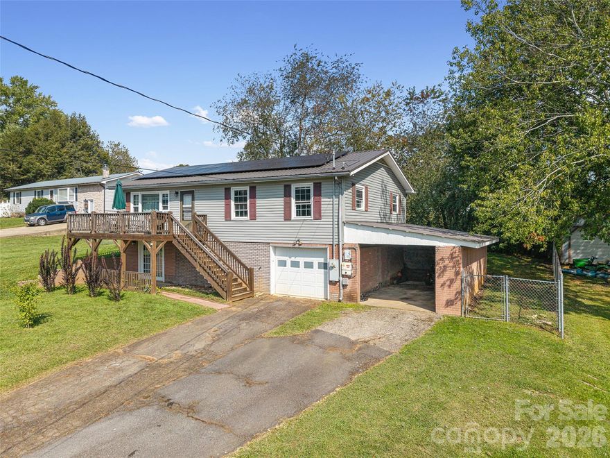 Situated just less than 30 minutes from vibrant Asheville, NC, this beautiful 3-bedroom, 1-bath brick and vinyl home is nestled in a well-established neighborhood located in the quaint mountain town of Clyde. Meticulously maintained and freshly painted, it boasts a kitchen equipped with stainless steel appliances, gleaming granite countertops, and a stylish tile backsplash. The basement level offers a brand new mini-split for efficient heating. Breathtaking mountain views from the front porch are yours thanks to its desirable west-facing orientation. The fully fenced, private backyard provides an escape to unwind at the end of the day! With a durable metal roof featuring solar panels, an oversized 1-car garage, and an attached carport guarantee ample room for parking and storage. Come home to where history and charm blend with modern suburban living that make coming home a true delight!