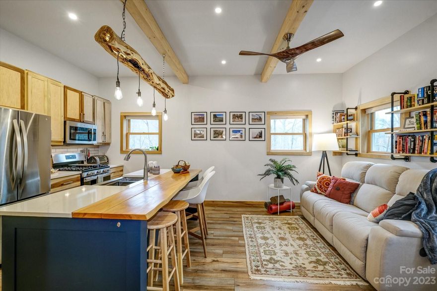 Incredible opportunity to own a custom-built Barndominium minutes from the Blue Ridge Parkway! The durable metal structure spans 2400+/- sq ft and includes a quality-crafted home alongside a 1600+ sq ft garage/workshop. The home features luxury vinyl plank floors and custom poplar cabinets, while the garage/workshop is equipped with 16' ceilings, oversized garage doors, and vent fans - making it an ideal setup for hobbyists or professionals looking for ample workspace! The home and garage/workshop feature a two-zoned hydronic radiant floor heating system. The 10+ acre property is easy to access via a paved road and has well-maintained gravel driveways that lead to multiple build sites, including an RV/tiny home pad with power, water, and septic hookups. An old logging road loops the property, making it perfect for a leisurely walk. Conveniently located 35-40 minutes from Asheville and under 15 minutes to both Sylva and Waynesville. Virtual tour, video, and features list are available!