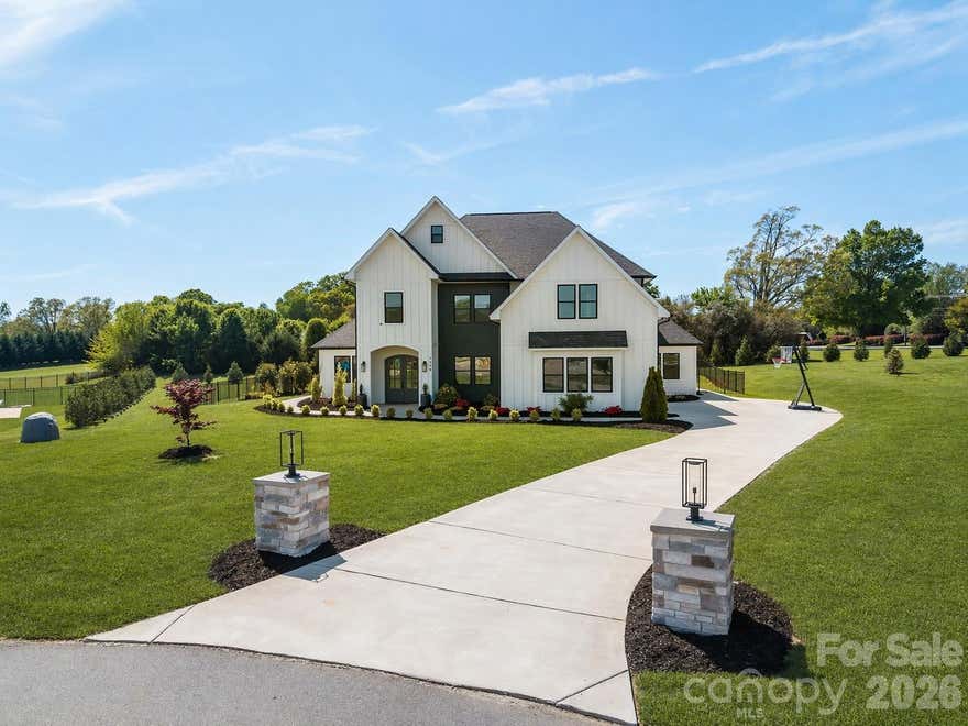 Private Executive Home with Board & Batten Exterior, 12’ Ceilings & In-Law Suite on Nearly 1 Acre in Mooresville. Welcome to this beautifully designed 4-bedroom, 4.5-bathroom home offering over 4,495 square feet of refined living space, perfectly situated on a private and expansive lot in Mooresville. The home’s board and batten exterior creates a clean, modern farmhouse-style presence that immediately stands out, while the interior delivers an elevated experience from the moment you walk in. Featuring 12-foot ceilings and 8-foot doors on the main level, the home offers a sense of openness, scale, and architectural detail rarely found at this price point.
The thoughtfully designed layout provides generous living spaces, abundant natural light, and flexibility for both everyday living and entertaining. A standout feature of this property is the private in-law suite, complete with its own separate entrance, full bathroom with shower, and sink—ideal for extended family, guests, or a private office or workspace. Set on nearly an acre, the property offers space, privacy, and endless potential for outdoor living, entertaining, or future customization. Whether hosting or enjoying quiet time, this home delivers a rare combination of comfort and functionality. Conveniently located just minutes from shopping, dining, and major access routes, this home offers the perfect balance of accessibility and private retreat-style living. A rare opportunity to own a spacious, modern home with high-end architectural features—ideal for professionals, business owners, or families seeking space, privacy, and flexibility.
