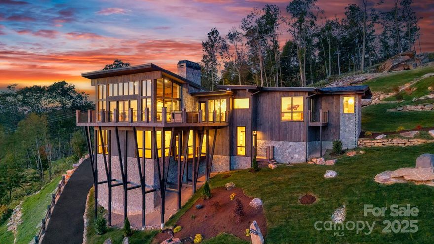 Seize the Rare Opportunity to own "Sunset in Paradise", a $4.5 million Masterpiece nestled in the Elite
Sunset Section of The Lodges at Eagles Nest. This architectural triumph redefines luxury mountain living
with unparalleled design and craftsmanship. Meticulously crafted over 3 years, this 1.202-acre estate
blends rugged natural splendor with exquisite elegance, offering 4,959 sq. ft. of heated living space & a
593 sq. ft. 2-car garage w/ modern frosted glass doors. Perched at an elevation of 4,400 feet above sea
level, it commands Breathtaking Panoramic views from North Carolina to Tennessee, where Mesmerizing
Sunsets Ignite the Senses. The exterior radiates modern mountain opulence w/ white pine-stained wood
siding, expansive floor-to-ceiling windows, & rustic metal beams. A $250,000 investment in bespoke
landscaping featuring natural boulders, custom-designed lighting, and intricate hardscaping creates an unforgettable first impression. Unwind on the expansive deck, where a state-of-the-art hot tub sets the
stage for starry nights, framed by hand-laid wooden beams and stone pillars that showcase Awe-
Inspiring Vistas. Step through the Grand Custom Glass front door, greeted by a dazzling chandelier
illuminating the great room. Soaring two-story glass panels bathe the space in natural light, framing the
majestic scenery. Nickel gap white pine-stained ceilings, rustic beams, light-toned floors, hand-laid
stone, & custom rusted metal gas fireplace marry rustic charm w/ contemporary elegance. The Gourmet
Kitchen is a Chef’s Dream, boasting a marble waterfall island, premium stainless-steel appliances, & a
wine cooler w/ Formal Dining. Downstairs, a custom-made bar, a wine cooler, & versatile bonus room
ideal as a movie theater, family haven, or game lounge elevate entertainment to new heights. Custom
Viewrail metal staircase railings seamlessly connect the outdoor deck to the interior, complemented by
handcrafted wood ceilings, stone accents, and glass windows that blend exterior grandeur with indoor
luxury. The estate features five lavish bedrooms, four full bathrooms adorned with hand-laid stone,
marble, and bespoke tiles, as well as one half-bath. The main floor primary suite is a sanctuary,
featuring a spa-inspired bathroom and an adjacent utility room. Commissioned Artwork and Lavish
Furniture throughout elevate the home’s handcrafted allure. The garage, with its hand-painted bronze
epoxy flooring, exudes artistry. Within the gated Eagles Nest community, indulge in a lifestyle of
unmatched vibrancy with ATV and hiking trails, a ropes course, playground, dog park, mini-golf, disc
golf, archery, a multi-use sports field, and courts for volleyball, basketball, and pickle-ball. Savor
luxurious amenities like Eagles Nest Winery, a cutting-edge fitness center, two helicopter pads, dining at
Epic Chophouse, Sportsman’s Grille, and BBQ Pavilion, a convenient Dollar General, and an outdoor
amphitheater hosting captivating seasonal concerts, Elk River access with over 4,000 Feet of
water-frontage for World-Class Trout Fishing! "Sunset in Paradise" is not just a home, it’s a Once-In-A-
Lifetime Retreat where Luxury, Nature, and Architectural Brilliance Converge, offering an Unrivaled
Lifestyle Amid the Peaks. 4 YEAR HOME WARRANTY! Don’t miss the chance to own this Extraordinary
Estate. A neighboring 7,055 sq. ft. property, listed as MLS #258143, is also available for purchase, 
presenting a Rare Opportunity to create a Main and Guest House Legacy.