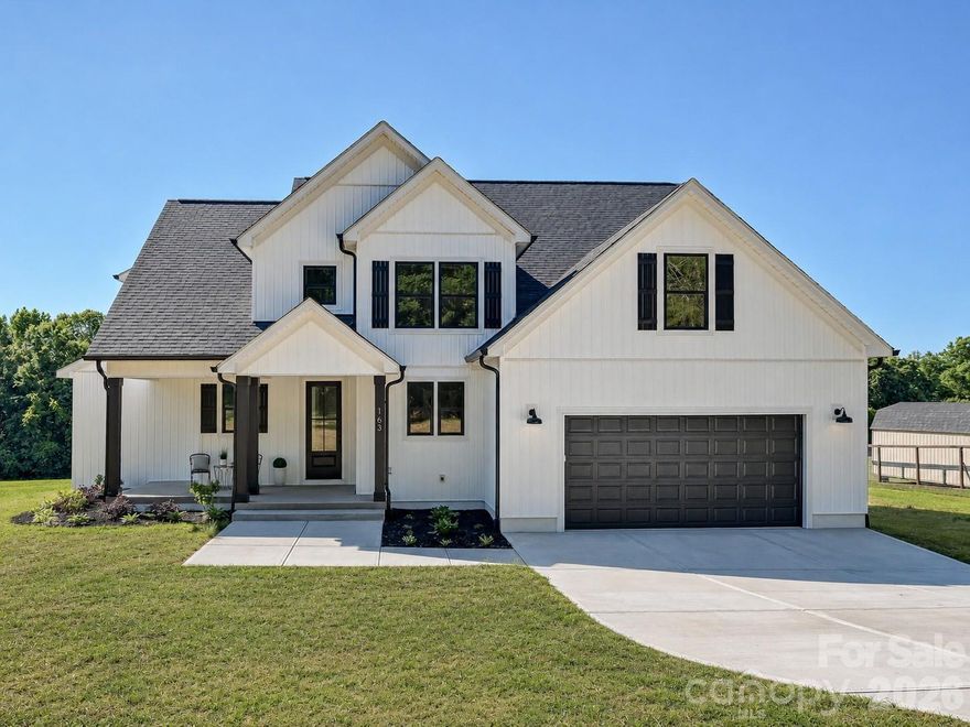 Nestled on a spacious homesite with a peaceful tree-lined backdrop, this stunning, custom built, new construction home blends timeless design with today’s most sought-after features. Step inside to an open-concept layout filled with natural light, soaring ceilings, and designer finishes throughout. The chef’s kitchen impresses with quartz countertops, custom white cabinetry, a large center island, gas cooktop, walk-in pantry, and striking dark accent backsplash, all flowing seamlessly into the dining area and vaulted great room with cozy gas fireplace. The luxurious primary suite offers a private retreat with a spa-inspired bath featuring dual vanities, a freestanding soaking tub, oversized walk-in tile shower, and expansive walk-in closet. Generously sized secondary bedrooms, a spacious bonus room perfect for a home office, media room, or playroom, and beautifully appointed full baths provide flexibility for every lifestyle. Enjoy outdoor living year-round from the covered back deck overlooking the large backyard and serene wooded views. With modern farmhouse curb appeal, thoughtful details, and exceptional indoor-outdoor living, this home offers the perfect blend of comfort, style, and functionality.