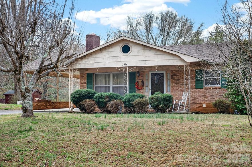 Affordably priced brick home with great potential! The architectural shingle roof was installed in 2021. Hardwood floors are featured in the living room and both bedrooms. The living room offers a large double windows for lots of natural light and a brick wood-burning fireplace with blower. The kitchen has a breakfast bar and a nice dining area. A covered front porch adds curb appeal and provides a great place to relax outdoors. The property includes both an attached carport and a detached metal carport for additional parking. The original third bedroom has been converted into a spacious main-level laundry room with cabinetry.
Downstairs, the full basement includes a wood stove and garage door access, offering extra storage or workspace. With a little exterior paint and shrubbery trimming, this home could really shine. Conveniently located between Lenoir and Morganton.