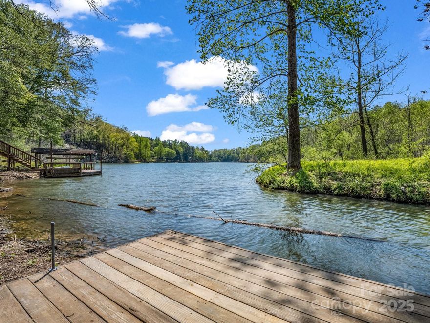 BALD MOUNTAIN LAKE & AMENITIES ARE OPEN! And this lovely lakefront home sits in a private cove on the north end of the one mile long, quiet non-motorized lake, part of the coveted Rumbling Bald on Lake Lure community. Launch your paddle board, kayak, or canoe off your private dock and paddle, take a swim, or fish in this beautiful, serene lake. The home has recently been updated with a brand-new roof and exterior paint finished in April of 2025. Interior has been updated in recent years and has a great layout with an open concept main level living space with a stone, wood burning fireplace as the centerpiece in the great room. Granite and stainless in the kitchen and an inviting dining area overlooking the level back yard with a fire pit. Primary en-suite bedroom, guest BR, & full guest bath on the main level. Two add’l BRs and a full bath are downstairs along with a family room and rec room with pool table. Screened porch off the back. Ample parking, and a great rental history.