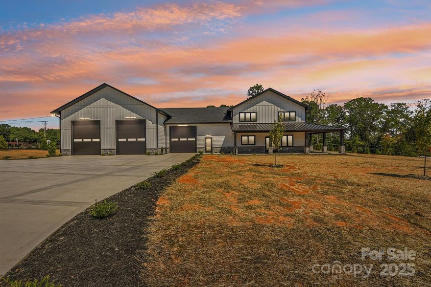 Welcome to Honeyman Estates, an exclusive gated enclave featuring just five luxury barndominiums—a rare opportunity to own one of the most innovative and desirable styles of homes in today’s market. More than just a residence, this property represents a new way of living: blending modern luxury with true practicality, designed for those whose lifestyle is as expansive as their vision. The garage is a masterpiece of its own, designed for more than just storage. With climate-controlled comfort, soaring 16 to 18-foot ceiling heights, epoxy-coated floors, and a powerful 400-amp service panel, this space is fully prepared to house your car collection, provide room for RVs and boats or even your very own indoor pickleball court! Spray foam insulation ensures year-round efficiency, while the impressive volume of the space allows for nearly limitless possibilities. This property offers not only the space but also the freedom to fully embrace your passions. From family living to hobby space, it redefines what home can mean. Step inside to find a stunning great room crowned by soaring vaulted ceilings that draw the eye upward and create an immediate sense of openness and grandeur. Vertical modern cable railing adds a sleek architectural touch, blending contemporary design with the rustic elegance of the barndominium aesthetic. The chef’s kitchen is a true centerpiece, featuring 42” shaker cabinets, quartz countertops, floating shelves, and premium appliances, crafted for both everyday meals and grand entertaining. Luxury vinyl plank flooring flows seamlessly throughout the home, leading to a striking 72” linear fireplace that anchors the living space with warmth and modern sophistication. Outside, the home’s timeless board-and-batten fiber cement siding pairs perfectly with architectural roofing, accented by standing seam metal for the covered porches, to create an aesthetic that is both classic and forward-thinking. Every detail has been considered, from the materials to the craftsmanship, resulting in a property that delivers enduring value and style. This barndominium is not just a home, it is a statement. A practical yet luxurious way of life that merges passion, functionality, and elegance under one roof. Honeyman Estates offers something incredibly rare: exclusivity, sophistication, and space to live life without compromise.