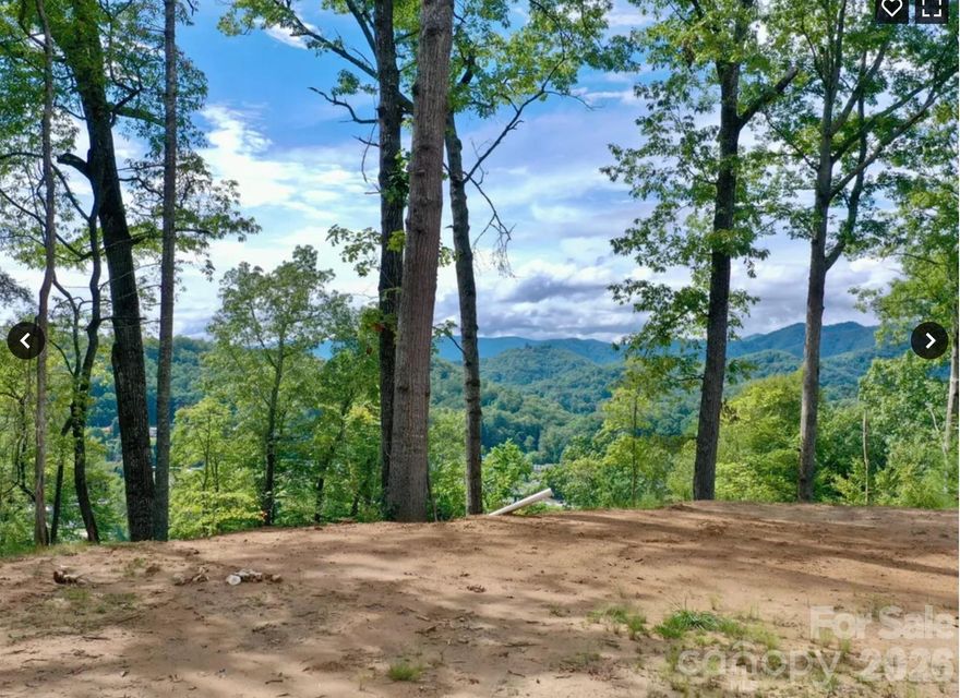 Perched above town, this private mountain retreat is accessed by a short scenic gravel driveway lined with trees, opening up to breathtaking mountain and city views. The elevated setting provides a peaceful, tucked-away feel while still being incredibly convenient — just 2 minutes from Bryson City Bakery, Bryson City Outdoors Brewery, and Pasqualino’s, 3 minutes to the Post Office, Great Smoky Mountains Railroad and Hallmark-like downtown, 5 minutes to Ingles Grocery Store and Darnell Farms and in 10 minutes you are hiking in the Great Smoky’s National Park. World renown white water rafting and the Nantahala Outdoor Center is a scenic 15 minute drive away.

***Owners plan to pave the area near the entrance to their home at 75 Bacon and the initial turnoff from Bacon Dr. to the lot. Work is planned for April. 

Every detail has been prepared for your dream build: city water, underground power, and septic are already in place, along with a substantial, professionally installed house pad. This thoughtful groundwork ensures a smooth start to construction, whether you envision a luxurious mountain retreat, an income-generating vacation rental, or your forever home.

It’s the perfect blend of natural beauty, privacy, and easy access to everything Bryson City and the Smokies have to offer.