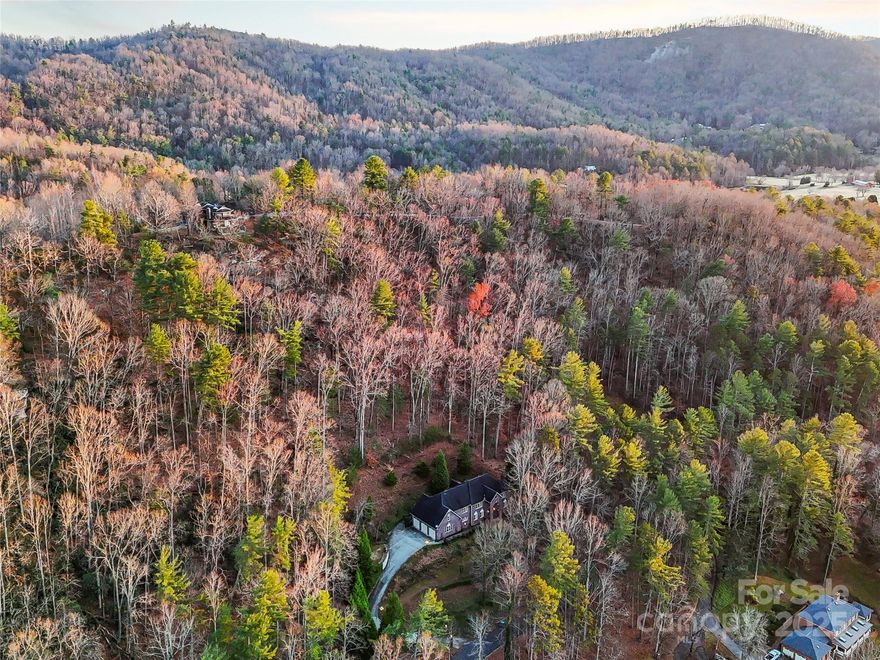 Welcome to Cedar Rock Estates, where luxury living meets the comfort and convenience of a country club lifestyle. This expansive 6,422 square foot home offers a refined mountain setting with wooded privacy, elegant finishes, and access to the full amenities of Cedar Rock Country Club, including golf, tennis, a pool, clubhouse dining, and year-round social events. Located minutes from the Blue Ridge Parkway and a short drive to Hickory, Boone, and Blowing Rock, this is one of Lenoir’s signature luxury homes.

The main level features a grand two-story entry with a sweeping staircase, formal living and dining rooms, a spacious kitchen with large island and breakfast area, a den with fireplace, a bedroom, laundry room, and a half bath. Crown molding, custom millwork, and large windows create a bright, elevated living experience.

Upstairs you will find the primary suite with a sitting area and fireplace, a generous bath with garden tub and walk-in shower, dual closets, and access to an additional laundry space. Two more bedrooms, two full baths, an exercise room, and a large bonus room complete this level, offering ideal flexibility for family living, work-from-home needs, or multi-generational arrangements.

The third floor adds another oversized bonus room and a full bath, perfect for a media room, guest suite, or private retreat. An elevator serves all levels and is currently non-functional, giving the next owner significant future potential.

Outdoor living includes a front porch, rear patios, and a private setting surrounded by mature trees. The sloped terrain provides a natural backdrop and low-maintenance landscape design, ideal for buyers who prefer privacy and outdoor relaxation over yard upkeep. A three-car garage, paved drive, and Starlink Internet service enhance everyday convenience. The driveway is steep, typical of the community’s terrain, and offers excellent privacy once at the top.

This home delivers an exceptional combination of size, quality, privacy, and lifestyle amenities within one of Caldwell County’s premier neighborhoods. Experience country club living, mountain proximity, and luxury space all in one address.