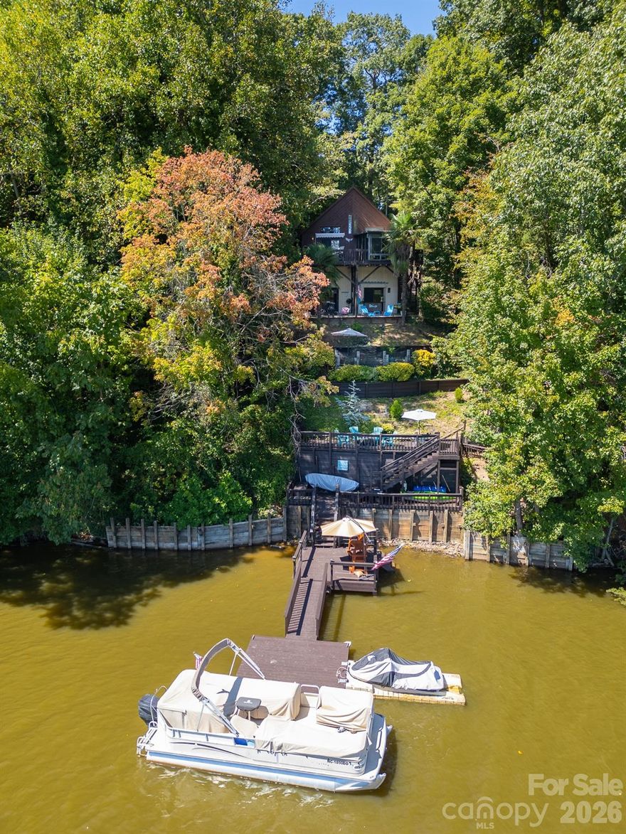 Lake life meets mountain life for oasis of relaxation, entertainment, & adventure! This lake front home with its own dock has expansive decks (freshly painted) & patio areas to soak in the most beautiful views of lush greenery and sparkling waters from the hot tub! Inside is as beautiful as the outside views with a remodeled kitchen featuring quartz counter tops, SS appliances, & peninsula bar seating that opens to dining & living areas. Vaulted ceilings & additional windows to allow natural light to pour into home add to the expanse and warmth of this home. Sunroom off dining area perfect for your morning coffee. Primary suite on main with granite counters in bathroom, built in drawers, & multiple closet spaces. Upstairs find spacious second bedroom or head to basement for office space and rec room or additional living space. Two more rooms & full bathroom that could serve for lodging. ROOF 2025! HVAC 2024! Storage building conveys. Neighborhood boat access around the corner!