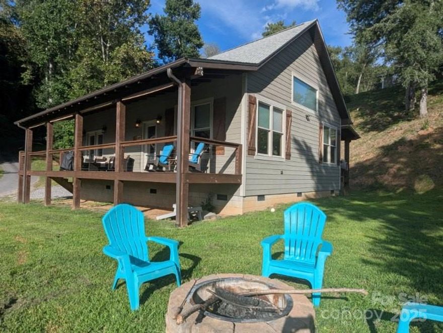 This beautifully furnished 2-bedroom, 2-bath home provides comfortable living on the Tuckasegee River. With modern finishes, thoughtful design, and numerous amenities, it’s perfect for both relaxing getaways and full-time residence. The included outbuilding offers additional storage and is 240 sq ft. The property’s proximity to local attractions and recreational opportunities makes it an outstanding choice for anyone seeking riverfront living. Close to WCU, Sylva, Dillsboro and Cherokee. Plenty of space for outdoor activities: play cornhole, relax by the firepit, or play in the water, fish or go tubing across the street to a strip of land that goes with this property or in the HOA common area. Currently used as a vacation rental. The kitchen features granite countertops, white custom kitchen cabinets, and an island with sink and dishwasher. Wood ceiling and wood and stone accent wall around the cozy fireplace. Wooden interior doors throughout the home. Primary bedroom includes an ensuite bathroom, double closets, and direct access to a covered porch with river views. Tiled shower extending to the ceiling with a clerestory window for natural light. Second bedroom is spacious, offering flexibility for guests or family. Second full bathroom with tub/shower and another clerestory window. Recessed lighting and full-size stackable washer and dryer. Hardy Board siding for low-maintenance living. Currently used as a vacation rental so book your appointment in advance. Home is not in the flood zone - just some lower land.