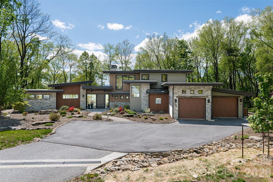 Embrace refined mountain living in this striking contemporary estate, where serenity and sophistication converge atop a rare flat mountaintop setting. Sweeping 180-degree Blue Ridge views unfold through expansive walls of glass, while timeless craftsmanship grounds the design. The living room stuns with soaring 20-foot ceilings, hand-hewn 125-year-old beams reclaimed from a Canadian barn, exposed custom metal supports and a dramatic stacked-stone fireplace with a concrete hearth. The gourmet kitchen is equally compelling, appointed with Thermador stainless steel appliances, Italian quartzite countertops and bespoke rustic alder cabinetry. A walk-in pantry and coffee bar, concealed behind a sliding knotty alder barn door, add function and charm. Flowing effortlessly into the dining area and sunroom with its stone fireplace, the home is designed for connection and entertaining. The main-level primary suite is a private retreat with mountain views, an oversized shower and a custom walk-in closet. Upstairs, two en-suite bedrooms feature artisanal tile and refined finishes. Outdoors, more than four acres offer landscaped gardens, trails, natural stone features and a fenced vegetable garden, all within the gated conservation community of Couch Mountain. This mountaintop property is conveniently 15 minutes from Asheville Airport, and halfway in between Asheville and Hendersonville for quick and easy access to both communities. With community-allowed seven-day rentals, this home is ideal for a lock-and-leave lifestyle with opportunities for potential income when not in use.