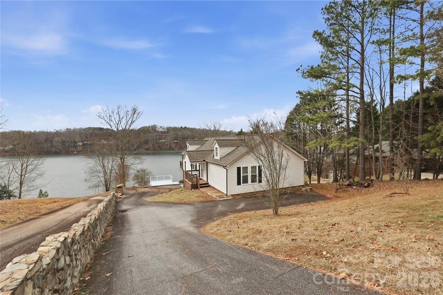 It’s never too early to start planning your lake life! Located in the gated Riverwalk community on Lake Lookout Shoals, this property offers the rare feel of living on a quiet, secluded lake. Situated on approximately 1.2 acres of waterfront this home perfectly positioned to capture gorgeous southwest lake views and unforgettable western sunsets. The spacious living room and eat-in kitchen both open directly to a large, elevated lake-view deck featuring composite decking and cable railing. Crown moldings in all main level living areas. Additional outdoor living spaces include a ground-level patio beneath the deck and a separate yard-level deck, all enjoying serene water views. The primary bedroom features a walk-in closet and an ensuite bathroom with walk-in shower and linen closet. The guest bedroom also includes a walk-in closet. A full, unfinished basement with 10-foot ceilings offers excellent potential for a game room or additional living space and includes built-in storage shelving. The oversized one-car garage is equipped with a workbench and a bathroom with shower, making lake days especially convenient. On-property lake access includes a beach area, boardwalk, and a floating boat dock with metal roof and boat lift. Several lake toys convey with the property, including a canoe and float tubes. Recent updates include new windows in 2024, a new roof in 2023, and new kitchen countertops in 2025. The property is served by a private well and septic system. The Riverwalk community offers gated roads, a private beach, picnic pavilion, boat launch ramp, day dock, and a locked boat storage lot. Conveniently located near golf, hiking, fishing, and easy day trips to Charlotte, Asheville, Boone, Blowing Rock, Statesville, and more. Property is located on a gated street and shown by appointment only.