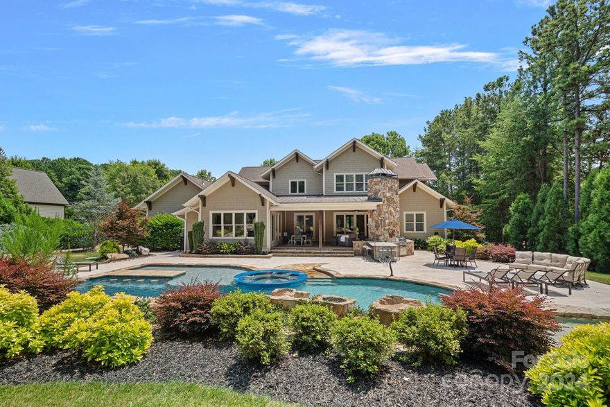 Welcome to one of the area’s most spectacular outdoor living spaces! This exceptional resort style oasis was expertly crafted by Charlotte Pools and Spas in 2021 and highlights the best in pool design and outdoor living. This one-of-a kind design features a grotto, slide, pool bar, multiple waterfalls, glass tile spa, sun shelf, fire rock features, special lighting effects, and more! A dream entertainer’s space also features a covered veranda with gas fireplace, outdoor kitchen with Blaze grill, pool bath, and sunken fire pit area. Classic architecture and timeless appeal continue inside where you will find an updated kitchen with double quartz islands, spacious great room with stone fireplace and coffered ceiling, flexible rec space, and main level primary suite. New roof, new carpet and fresh paint make this home turn key and ready to move in! Enjoy The Farms' amenities including pool, clubhouse, and tennis, all within easy access to Lake Norman. An extraordinary offering!