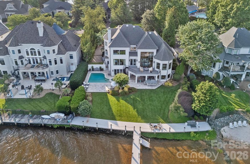 Experience designer luxury in this rare turn-key waterfront estate on one of the most coveted streets in The Peninsula. Meticulously updated and move-in ready, this 6,000+ sq ft home blends timeless elegance with modern comfort. Designed by a professional with exceptional attention to detail, it showcases stunning light fixtures and high-end finishes throughout. The open-concept kitchen flows seamlessly into a cozy family room and soaring two-story great room—ideal for entertaining and everyday living. Five spacious bedrooms and 6.5 spa-inspired baths span three beautifully finished levels. Enjoy breathtaking long-range views from modern windows, a resort-style backyard with pool, spa, outdoor kitchen, and covered patios. The walk-out basement features a guest suite, gym, and large family room. A deeded boat slip with covered dock and lift completes the ultimate Lake Norman lifestyle. Walk to the Yacht Club and minutes from The Peninsula Club.