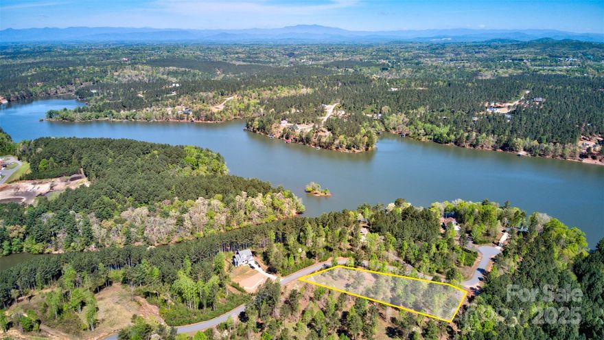 Build your dream home on this 1.34± acre corner lot in the gated community of Island Pointe at Lake Vistas—where Lake Rhodhiss and the Blue Ridge Mountains create a breathtaking backdrop. Elevated for privacy, this homesite captures long-range views of Table Rock and seasonal lake views, surrounded by the natural beauty of Western North Carolina. With underground utilities and paved community roads, every home in Island Pointe complements the area’s serene mountain-lake setting. Lake Rhodhiss is known for its clear waters and abundant recreation—you’re just steps from swimming, fishing, kayaking, and boating, with Castle Bridge public access only minutes away. The community also offers a private boat ramp, picnic area, and gated entry for added peace of mind.
Perfectly located between Charlotte, Asheville, and Blowing Rock (each about an hour away), this property offers the ideal mix of seclusion and convenience. Whether for a primary residence, vacation home, or investment, this lot provides the perfect setting to enjoy the best of mountain and lake living.