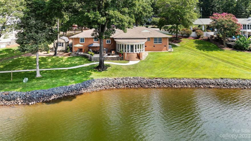 Stunning waterfront Property with tons of character and AMAZING views of Lake Wylie! Designed to enjoy lake living and the outdoors, this waterfront treasure features a gently sloping lot, mature trees, spacious yard, and long range views. You’ll love the light filled sunroom, paver patio, dock with lakeside seating and boathouse.  All fantastic spots for outdoor entertaining or just to relax and take in the glorious views. Easy living open floor plan boasts spacious formal dining and living room, lake facing great room with gas fireplace, 3 beds (one can be home office), 2 1/2 baths, & oversized 2 car garage.  Engage your inner chef in the dream kitchen with stainless steel appliances, center island w/ plenty seating, quartz & butcher block counters, and farm sink.  Come find your little piece of heaven! Convenient location minutes from shopping, dining, Uptown Charlotte, & airport.