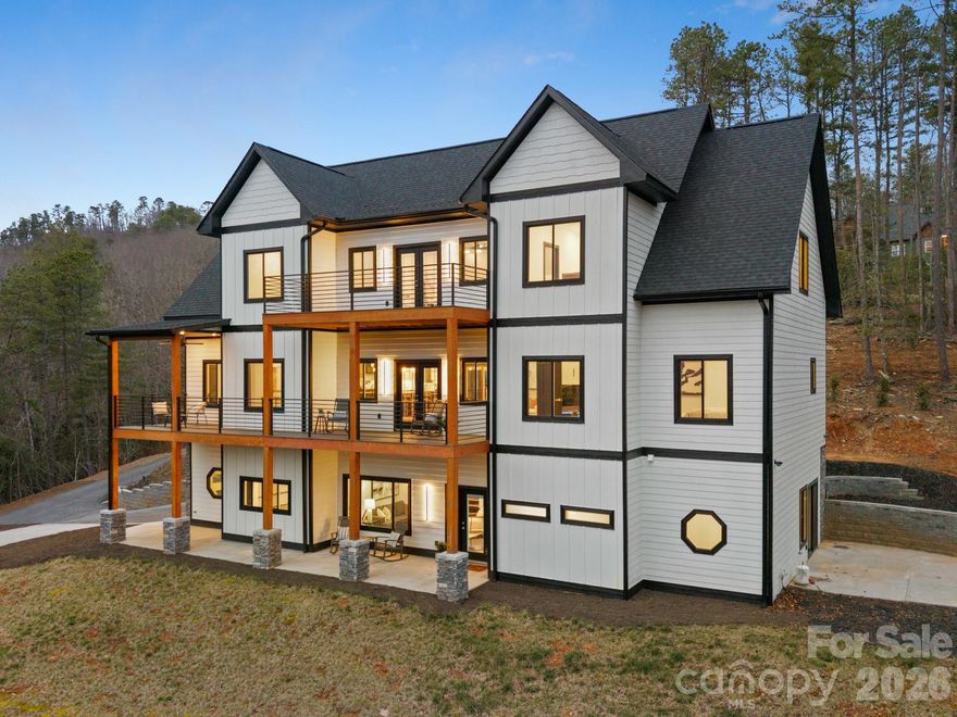 Luxury mountain living just minutes from Pisgah National Forest.
Located one mile from Turkey Pen Gap Trailhead and a short drive to Brevard, Hendersonville, and Asheville. This beautifully designed 4,000+ sq ft mountain home offers fireplaces, spa-like bathrooms, outdoor entertaining spaces, and year round mountain views all surrounded by some of the best hiking and biking in Western North Carolina. Imagine waking up to mountain views and stepping outside to some of the best outdoor recreation in Western North Carolina with hiking, mountain biking, river walks, and horseback riding practically in your backyard.

The first level welcomes you with a stone fireplace and built-ins, creating a cozy living area that could also function as a game room or entertainment space. There is plenty of room for a pool table, lounge seating, or even a bar area for hosting gatherings and celebrations. This level also features an additional primary bedroom suite with a corner fireplace and sliding doors that lead directly to the patio that is already set up for a future hot tub. The spacious spa-inspired bathroom includes dual vanities and a dramatic walk in shower that surrounds a soaking tub, creating a true retreat experience. A large walk in closet with washer and dryer hookups makes this level perfect for a guest suite or in-law living area.
As the illuminated staircase leads you upstairs, the second level opens up to beautiful south facing mountain views. The chef’s kitchen is the centerpiece of the home, anchored by a stunning waterfall granite island designed for cooking, gathering, and entertaining. CAFÉ™ ENERGY STAR® appliances, a hidden pantry, stainless range hood, and pot filler add convenience while maintaining a sleek, modern aesthetic. Cabinet lighting automatically illuminates when opened, and gold hardware paired with the marble tile backsplash adds a touch of luxury.
French doors open to a large covered deck, creating a seamless indoor/outdoor flow between the kitchen, dining area, living room, and outdoor entertaining space to perfectly host friends or enjoying quiet mountain evenings. A second laundry room and half bath are also located on this level for added convenience.
The main-level primary suite features a fireplace with a comfortable seating area and stunning mountain views right from your bed. The en-suite bathroom offers a soaking tub, large walk-in shower, and generous space to unwind after a day exploring the mountains. Two separate closets provide abundant storage for seasonal wardrobes and linens.
The third level offers incredible flexibility for modern living. A bright area at the top of the stairs works perfectly as an office, reading nook, or creative workspace. Nearby, a spacious room could serve as a fourth bedroom, studio, nursery, or additional office space, complete with a walk-in closet and nearby full bathroom.
Another large room on this level offers the perfect bonus space for a family room, game room, or kids’ hangout. French doors lead to a private deck where you can enjoy long-range mountain views year-round.
Also on this level is the third bedroom suite, featuring its own fireplace, seating area, walk-in closet, and private bathroom with dual sinks and a walk-in shower.
Outdoor living is just as impressive as the interior. Multiple decks and patios create inviting spaces to relax and take in the surrounding mountain scenery. The landscaping is designed for low maintenance living, while arborvitae trees provide backyard privacy without blocking the front mountain views.
Schedule your showing today and experience mountain living at its best.
