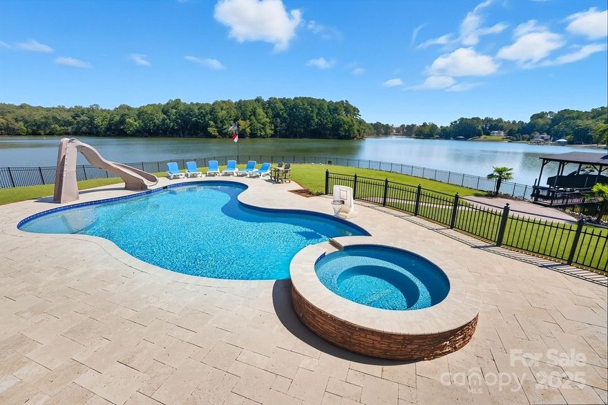 Welcome to Your Lake Wylie Paradise in Beautiful Belmont! Live the lakefront lifestyle you’ve always dreamed of in this stunning, full-brick custom home, perfectly positioned on a level point lot with panoramic lake views and protected conservancy land in the background.  Designed to embrace the outdoors and capture breathtaking water views from nearly every room, this property features a massive covered porch, swimming pool with hot tub, and lush, professional landscaping. Whether you're entertaining guests or unwinding with family, this space is ideal. Water lovers will appreciate the private boat ramp, spacious covered dock with boat lift, and two jet ski lifts—ready for endless lake adventures. From the moment you enter the grand foyer with its sweeping staircase, you’re greeted by gorgeous hardwood floors, rich crown molding, and thoughtfully designed living spaces. The formal dining room offers the perfect setting for both elegant dinners and casual gatherings. The Great Room boasts soaring ceilings, a cozy gas fireplace, custom built-ins, and large windows that flood the space with natural light and stunning lake views. The gourmet kitchen features stainless steel appliances, double ovens, granite countertops, a center island, and a sunny breakfast area. Just off the kitchen, the fabulous sunroom invites you to linger with your morning coffee, read a book, or simply soak in the tranquil lake views. It would also make a perfect home office. Relax in the main-level primary suite, complete with tray ceiling, serene lake views, and a spa-like bath with premium finishes. Upstairs, you’ll find two additional bedrooms, two full baths, a spacious bonus room, and a flex room perfect as an office, 4th bedroom, or playroom. Abundant storage throughout ensures everything has its place. There is even a large workshop/storage area in the crawl space.  This beauty features a high-efficiency geothermal heat pump for HVAC, along with an electric water heater supplemented by geothermal auxiliary heating. Fully fenced backyard and in-ground irrigation. Recently renovated primary bathroom, fresh paint, and new carpet.  Nestled in the charming town of Belmont, enjoy the best of both worlds—peaceful, small-town living with convenient access to Uptown Charlotte, the airport, and major shopping destinations, just a short drive away.